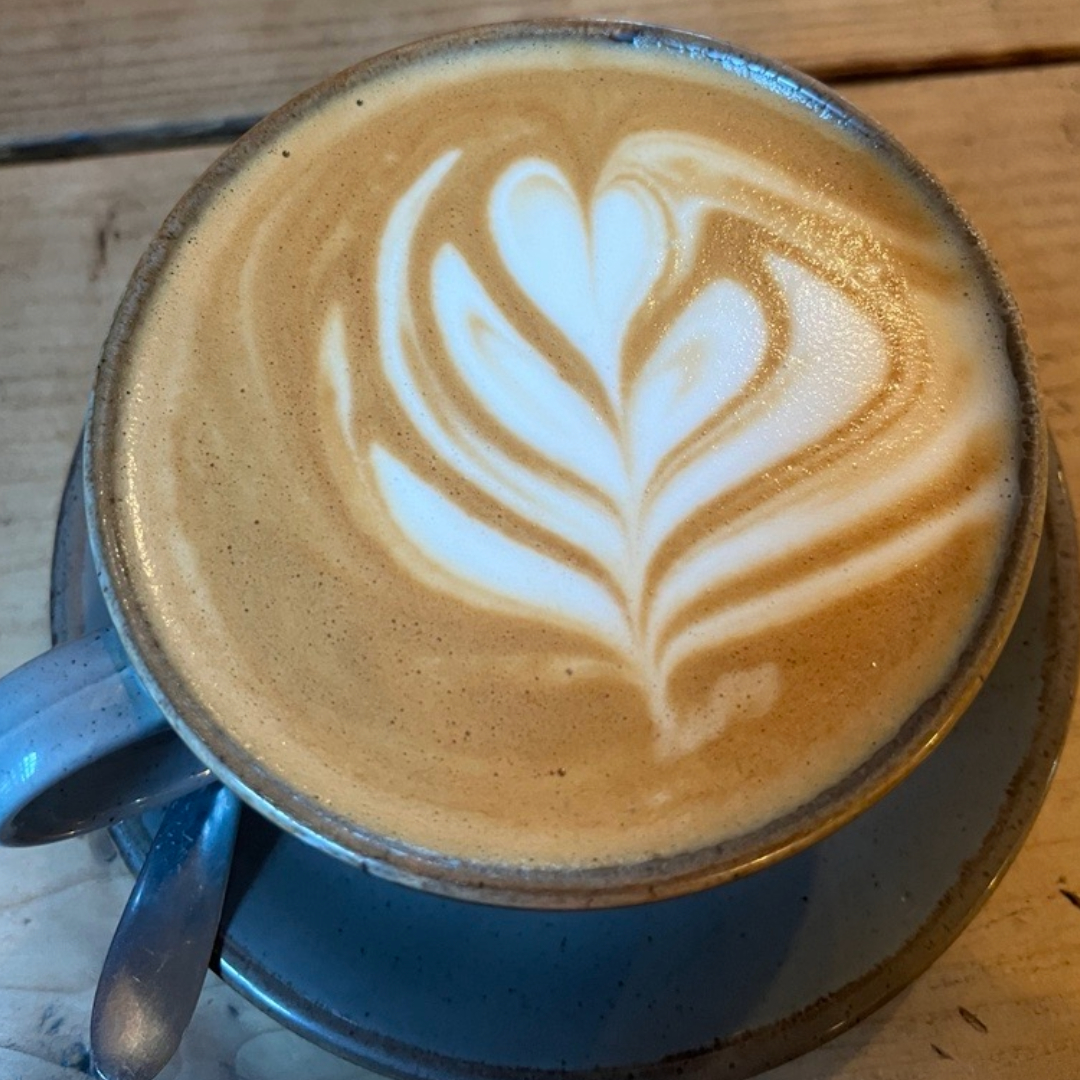 Image shows a cup of coffee with a heart design on it.